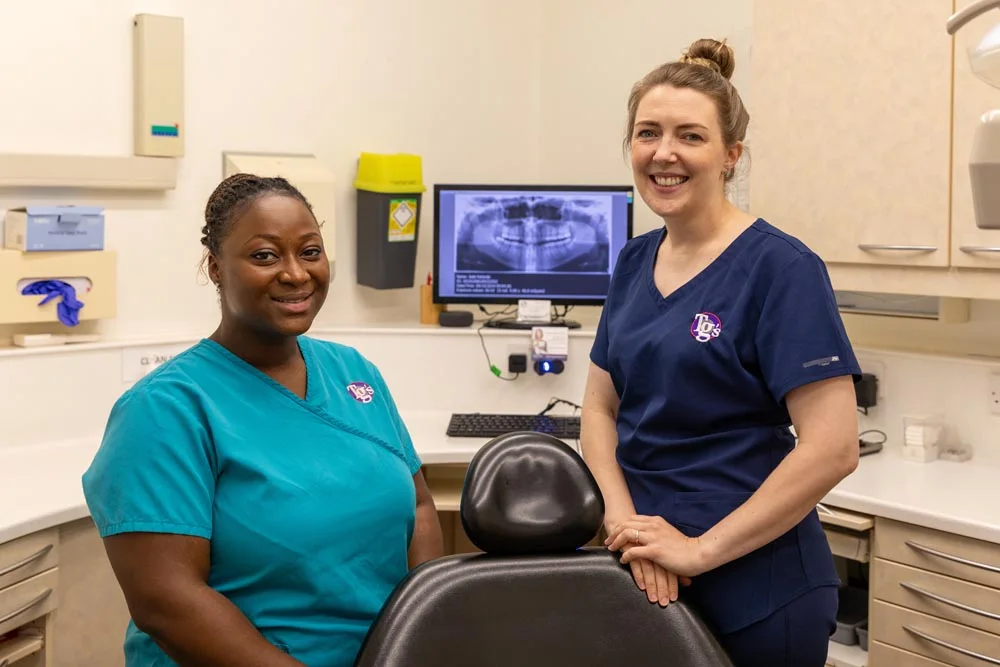 Two TG's Dental Suite team members beside a panoramic dental X-ray on screen