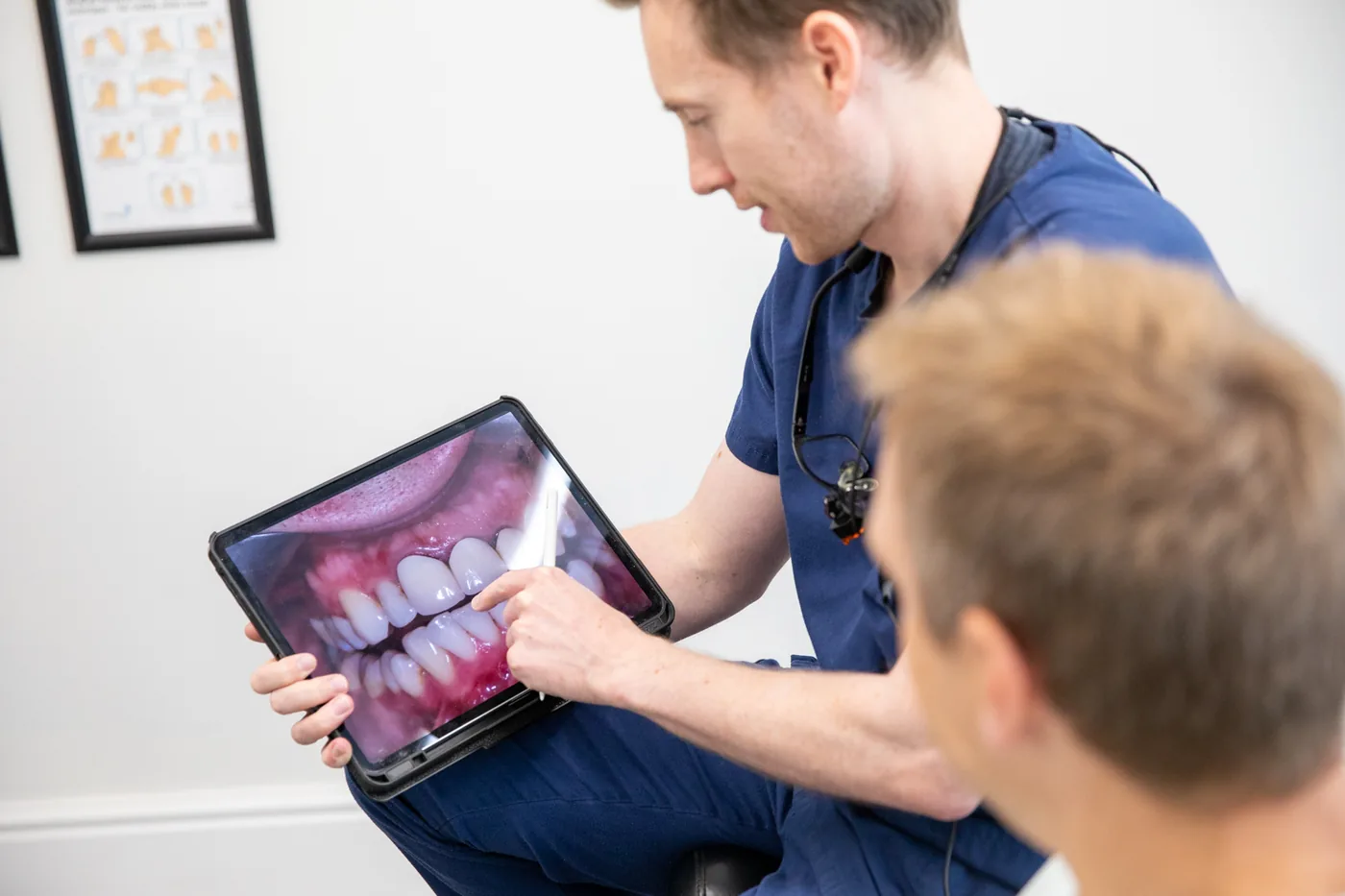 A dentist at TG's Dental Suite talking a patient through an intraoral photo on a tablet