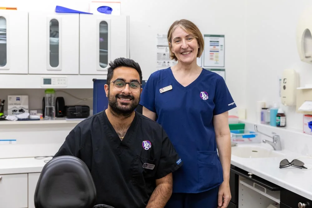 Two TG's Dental Suite clinicians in branded scrubs, smiling together in a treatment room
