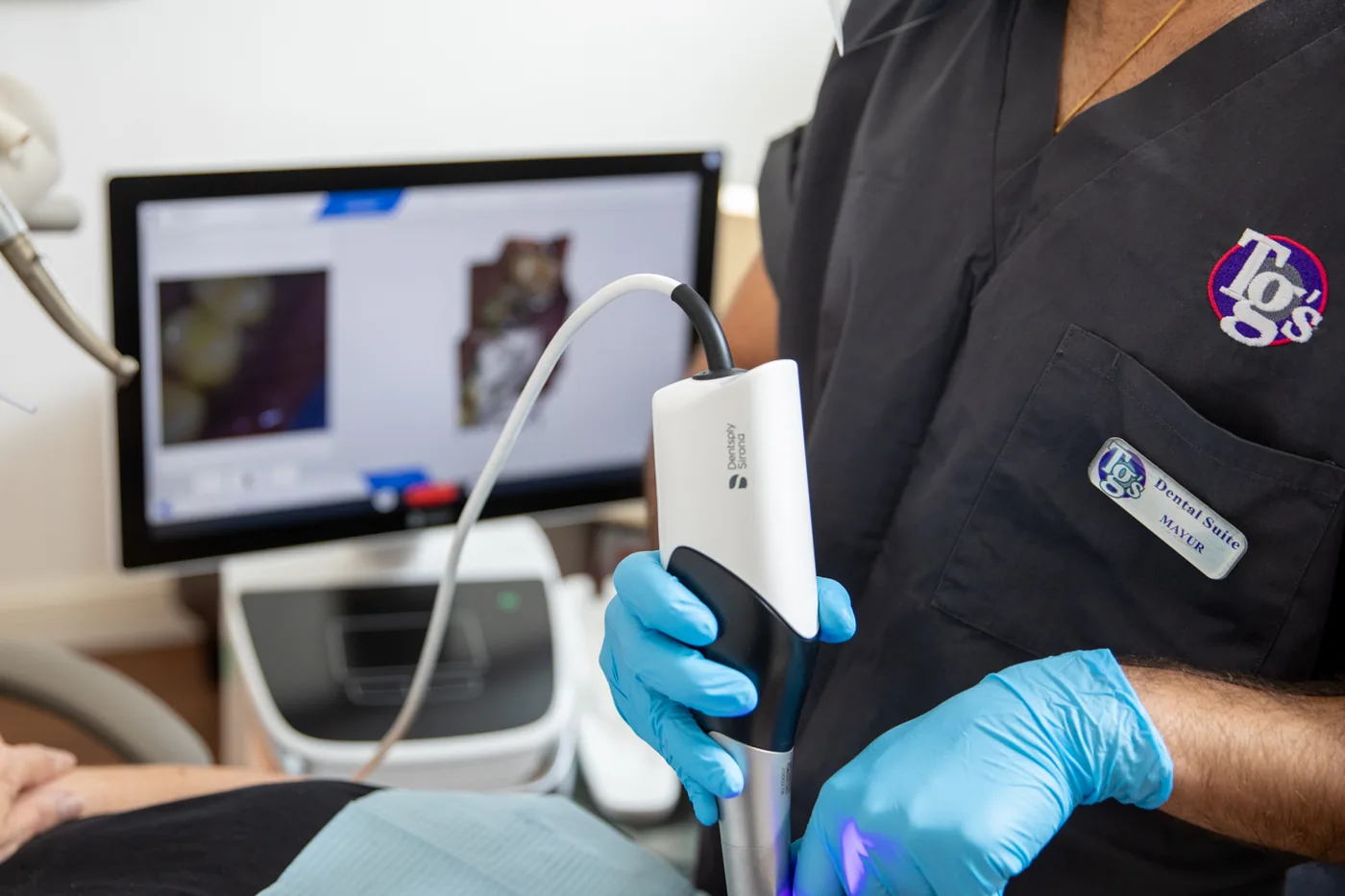 A TG's Dental Suite clinician holding an intraoral scanner wand, with the scan on the chairside screen